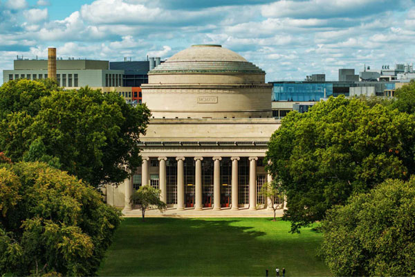 MIT campus with iconic dome building surrounded by green trees and sky